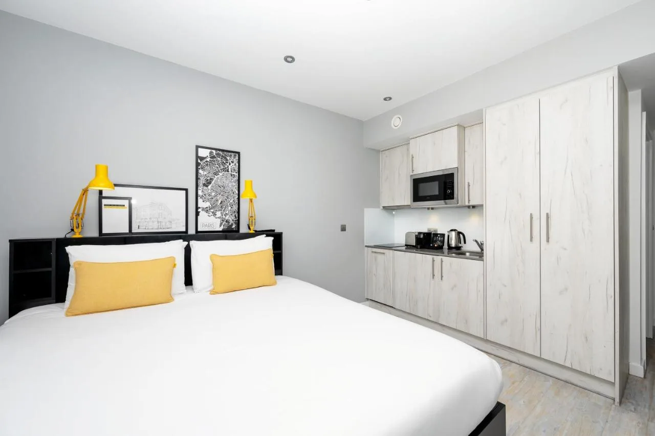 a white bedroom with a large white bed and yellow pillows at Staycity Aparthotels Liverpool Waterfront in Liverpool